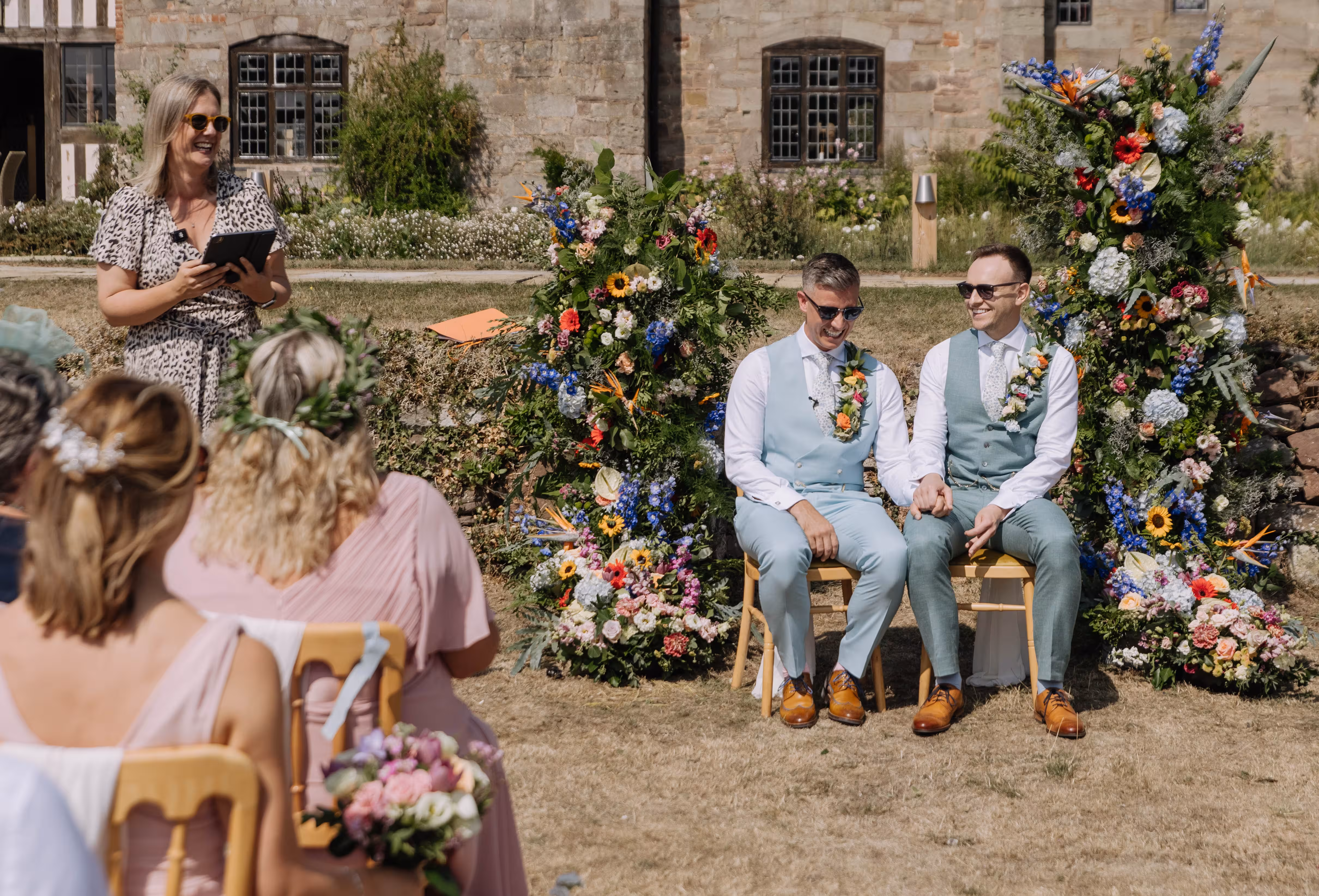 Kate Rostance Celebrant leads ceremony as Rod and Dan sit together at Brinsop Court wedding.