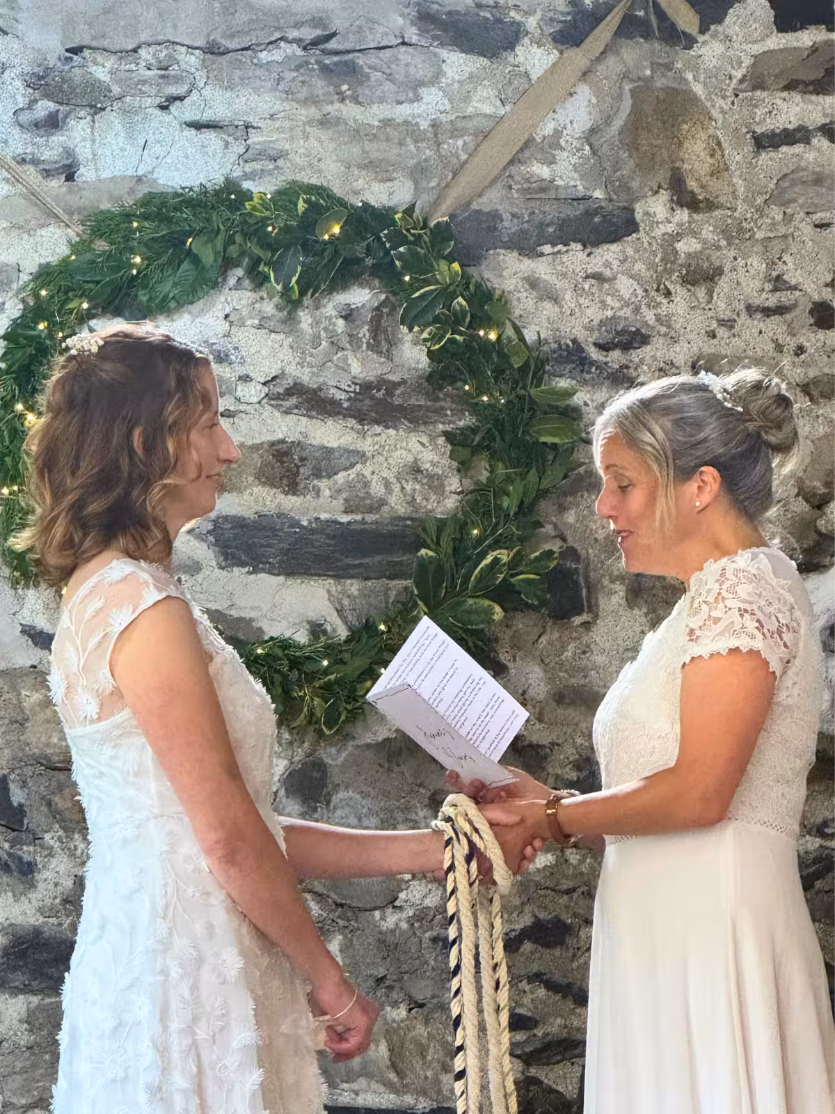 Clair and Janine exchanging vows and handfasting cords during their humanist wedding ceremony at Llyn Gwynant Barns in North Wales.