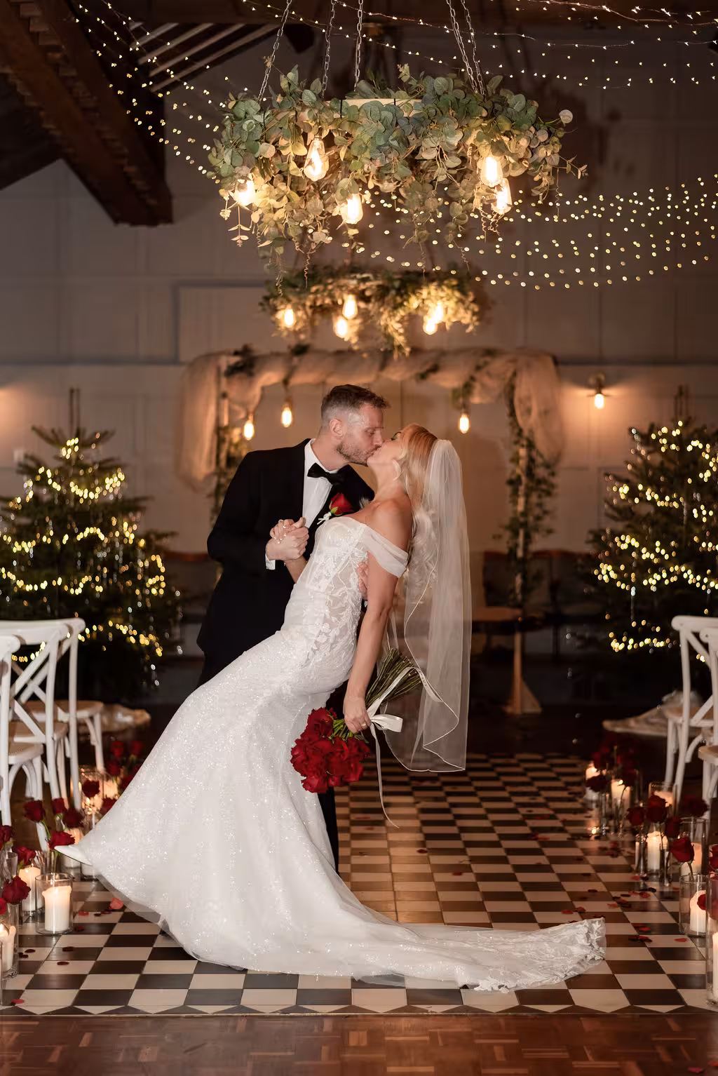 Bride and groom share their first kiss during a Humanist symbolic wedding ceremony at Larkspur Lodge in Knutsford, Cheshire beneath floral chandeliers and twinkling lights.
