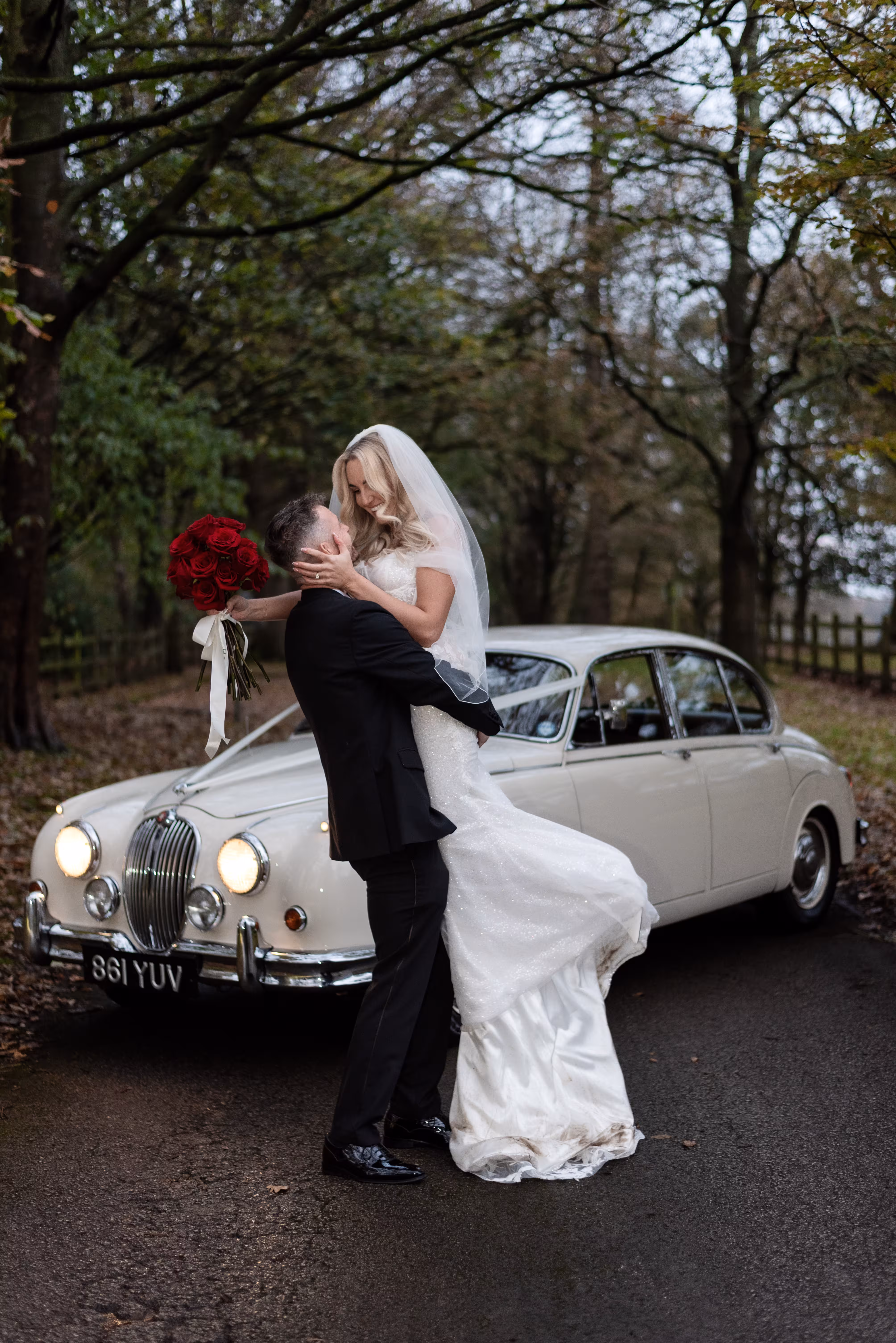 Couple sharing their first kiss during their Humanist wedding ceremony at Larkspur Lodge, followed by a romantic portrait beside a vintage wedding car.