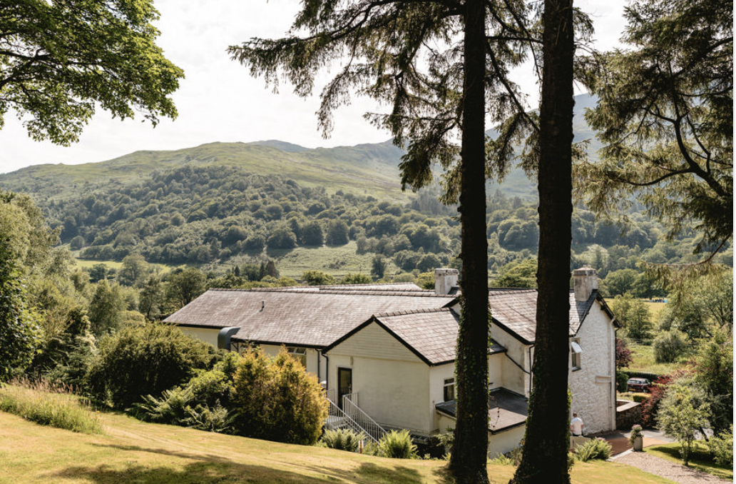 Tŷ Afon river house wedding venue seen through pine trees, with valley and mountain views across Eryri in North Wales