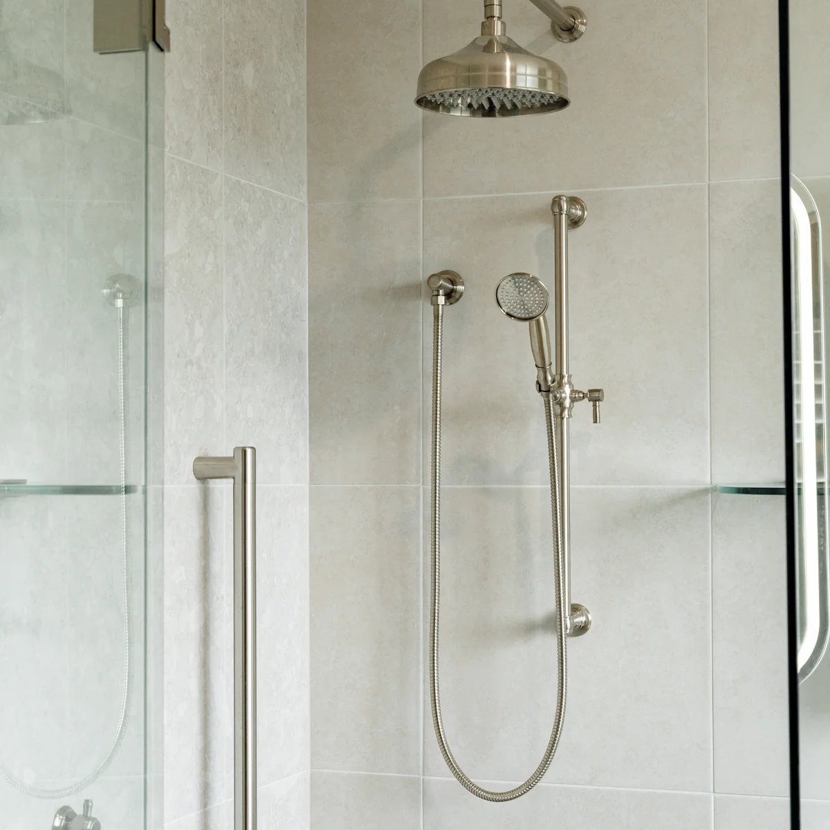 Brushed nickel rainfall showerhead with handheld attachment and frameless glass shower screen