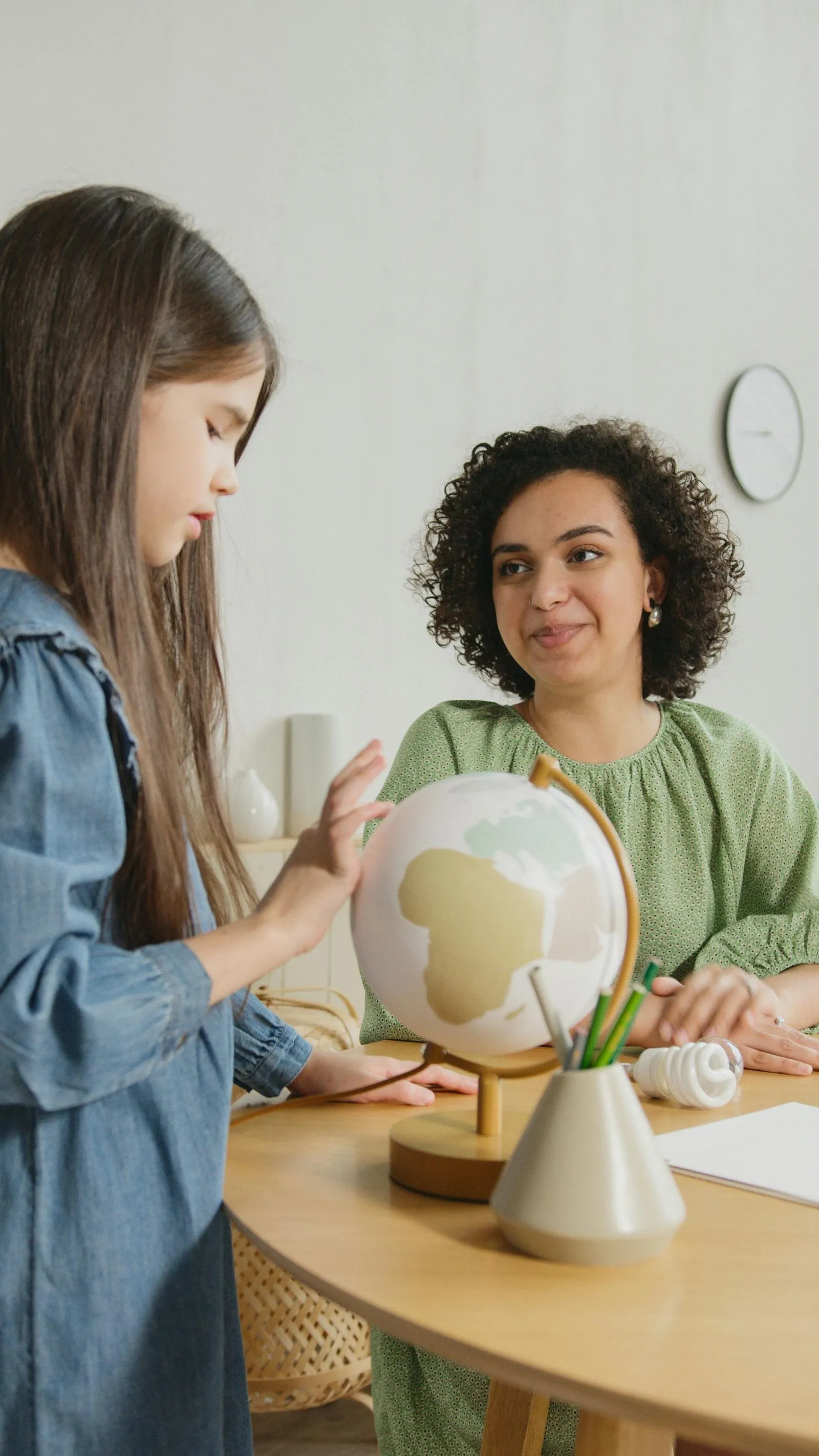 A teacher is showing a globe to a student