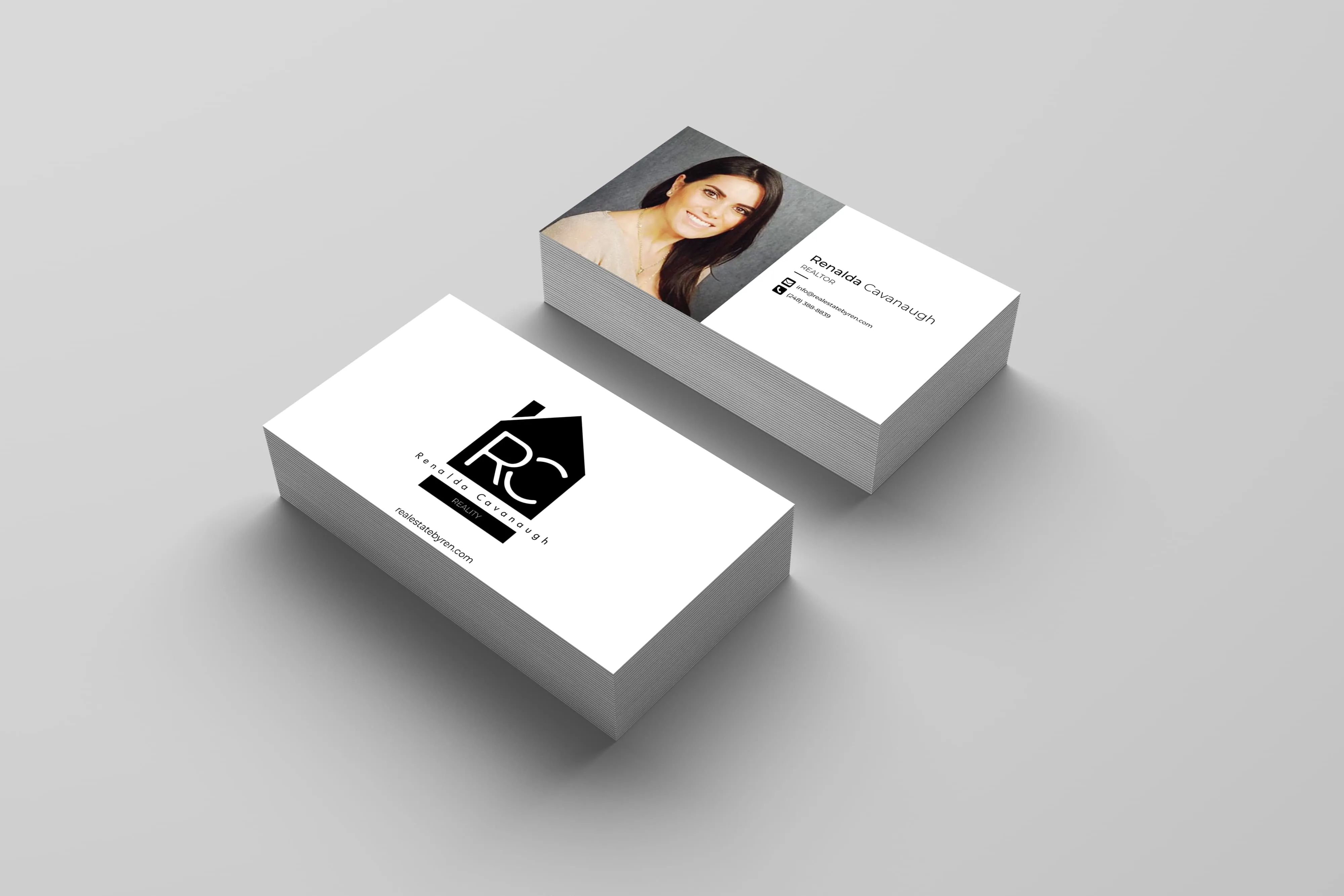 Stack of business cards for Renalda Cavanaugh, realtor, showing her photo, contact details, and a black house-shaped logo with initials RC.