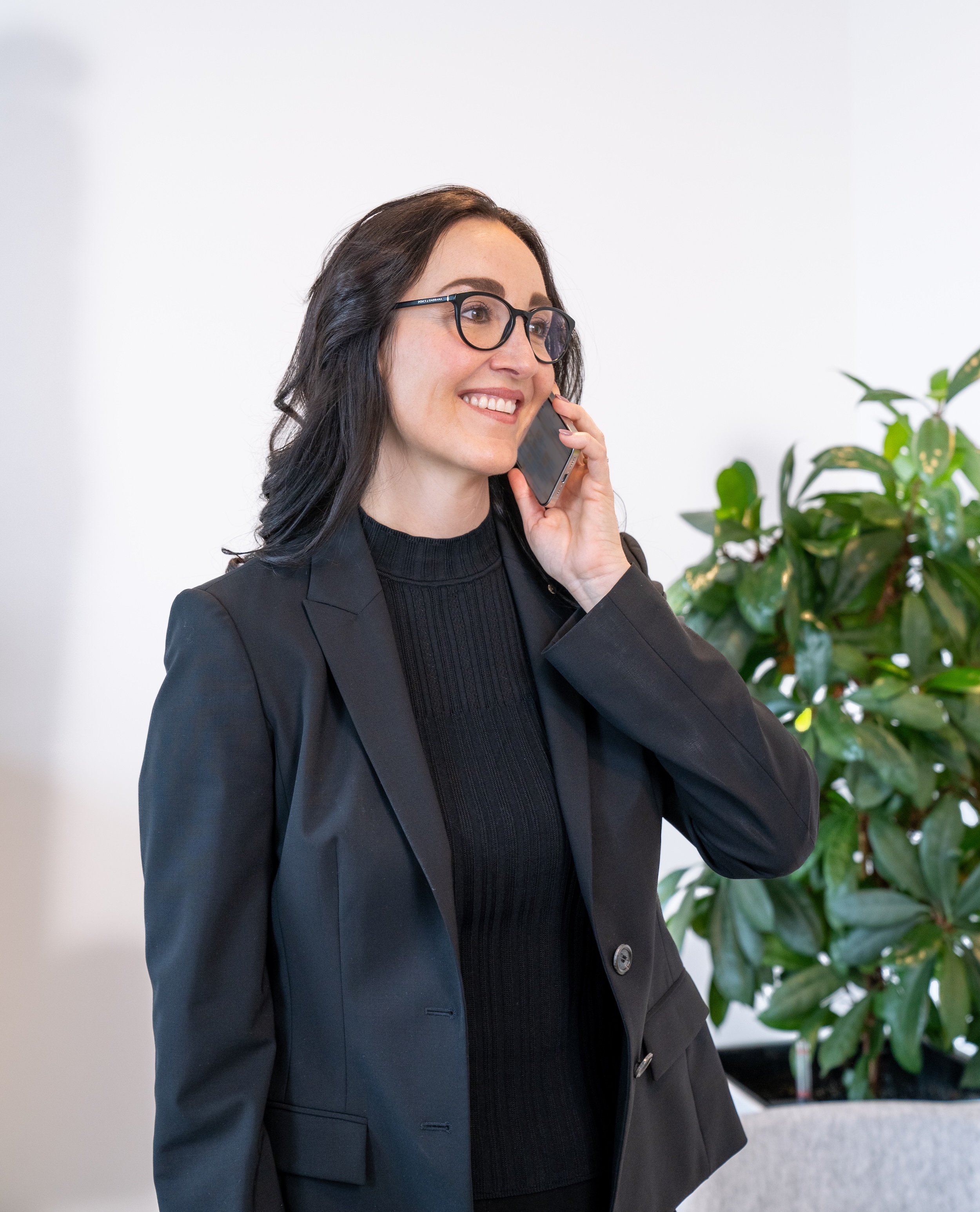 Porträt einer Frau im schwarzen Outfit im Büro, Hand am Kinn.
