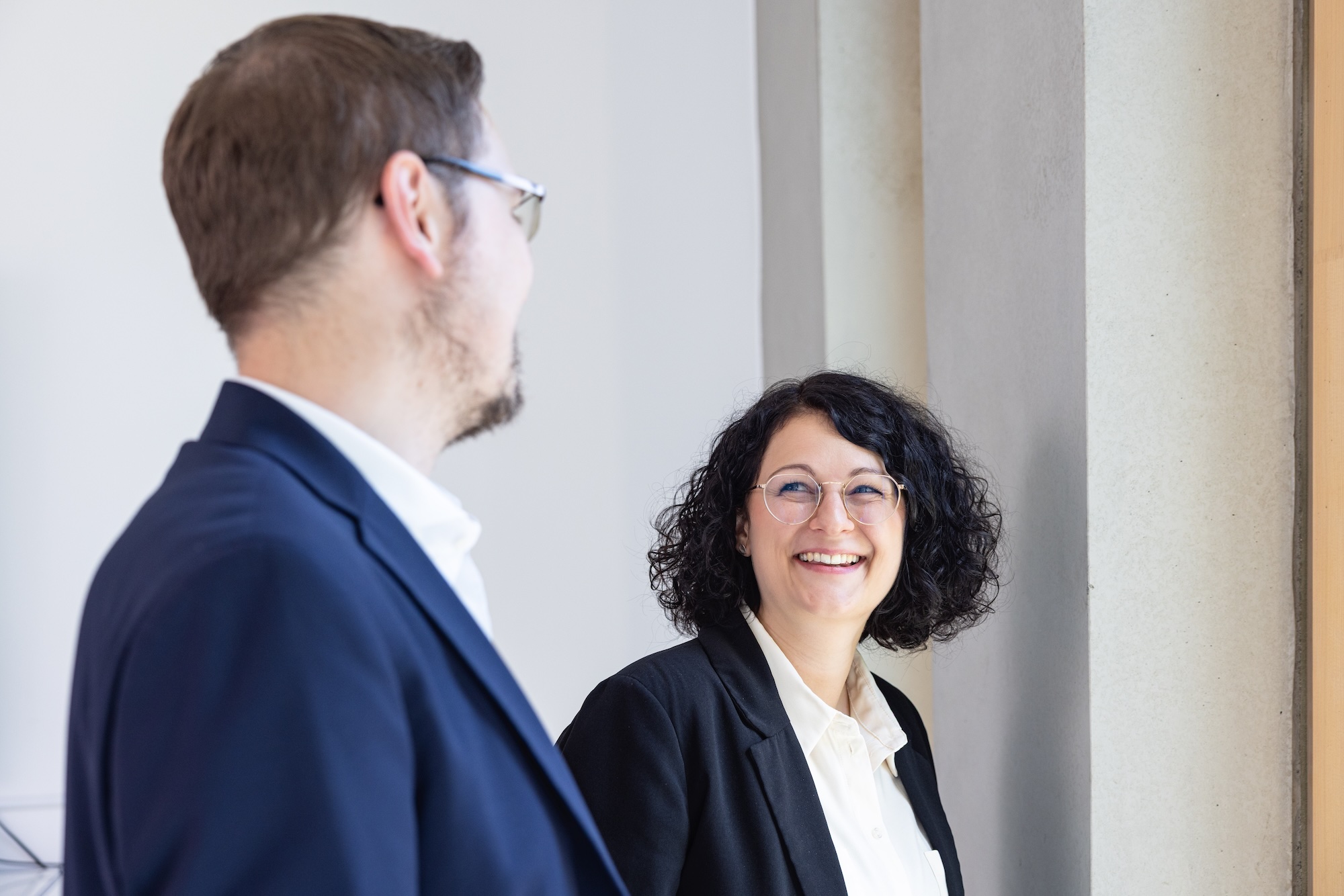 Zwei Personen im Büro im Gespräch, eine Person steht im Vordergrund.