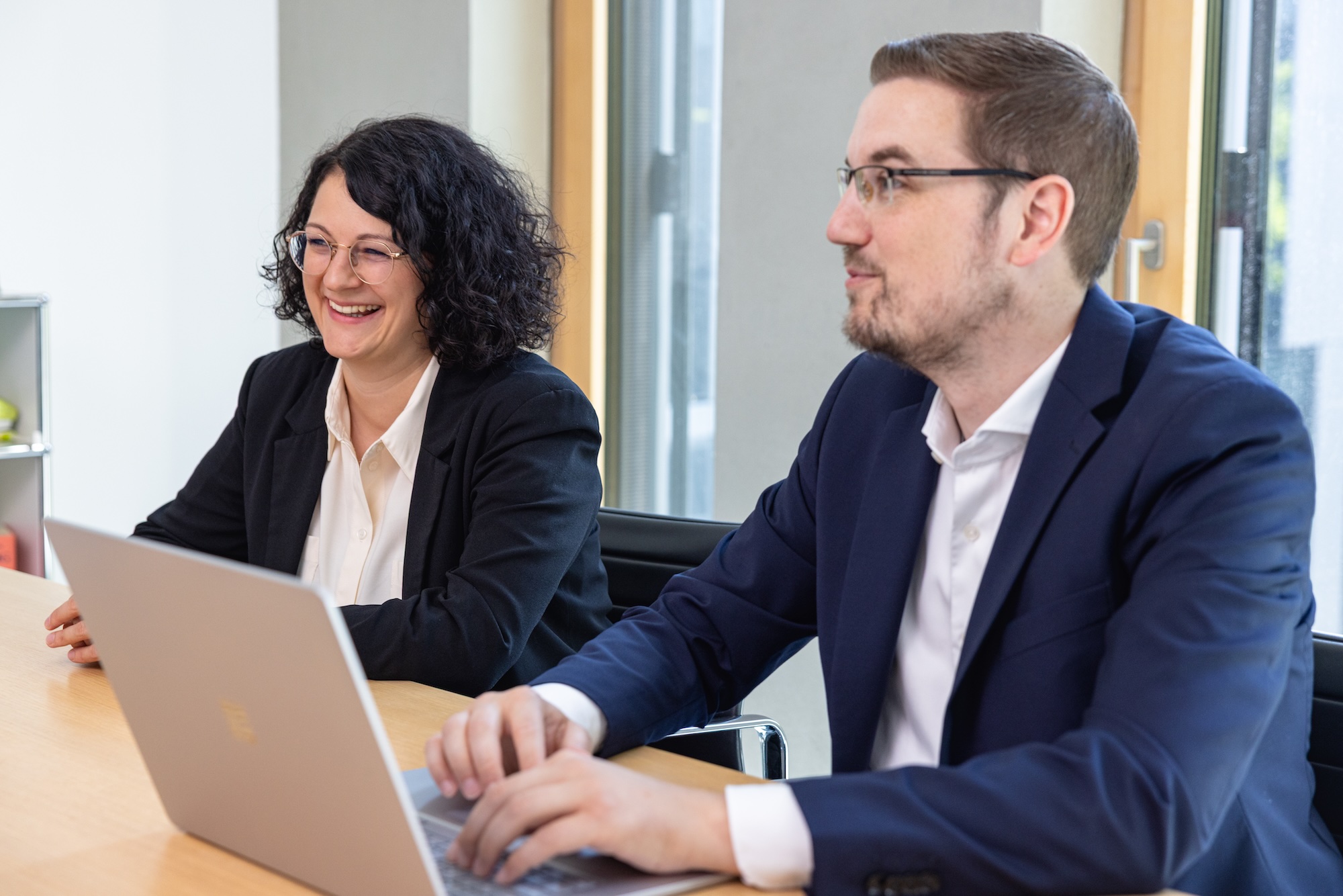 Zwei Personen im Büro arbeiten gemeinsam am Laptop.