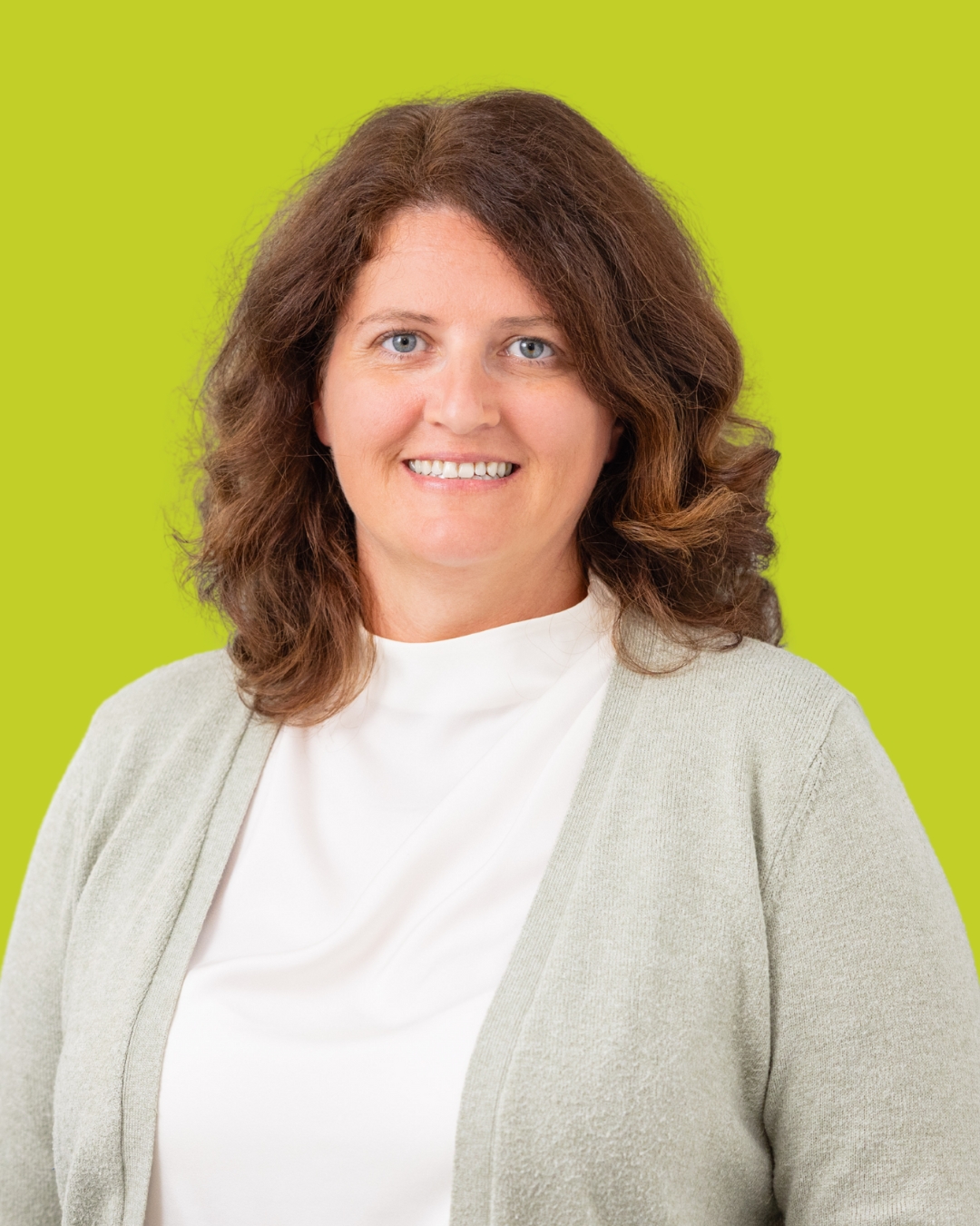 Porträt einer Frau in hellem Oberteil vor grünem Hintergrund.