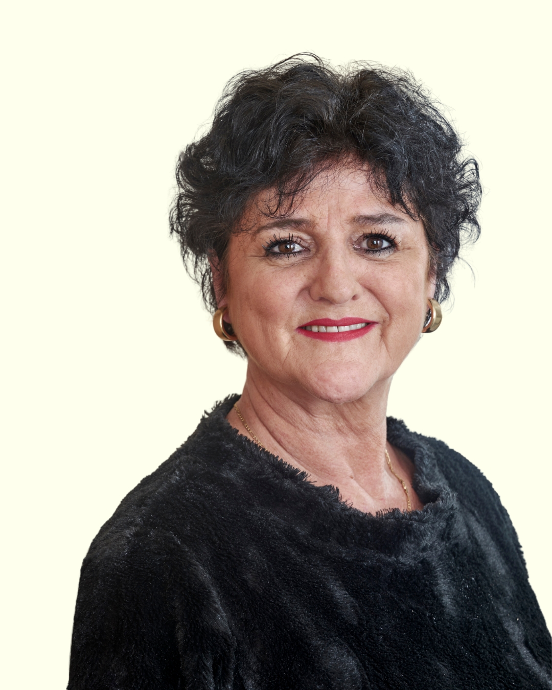 Porträt einer Frau mit kurzen dunklen Haaren vor hellem Hintergrund.