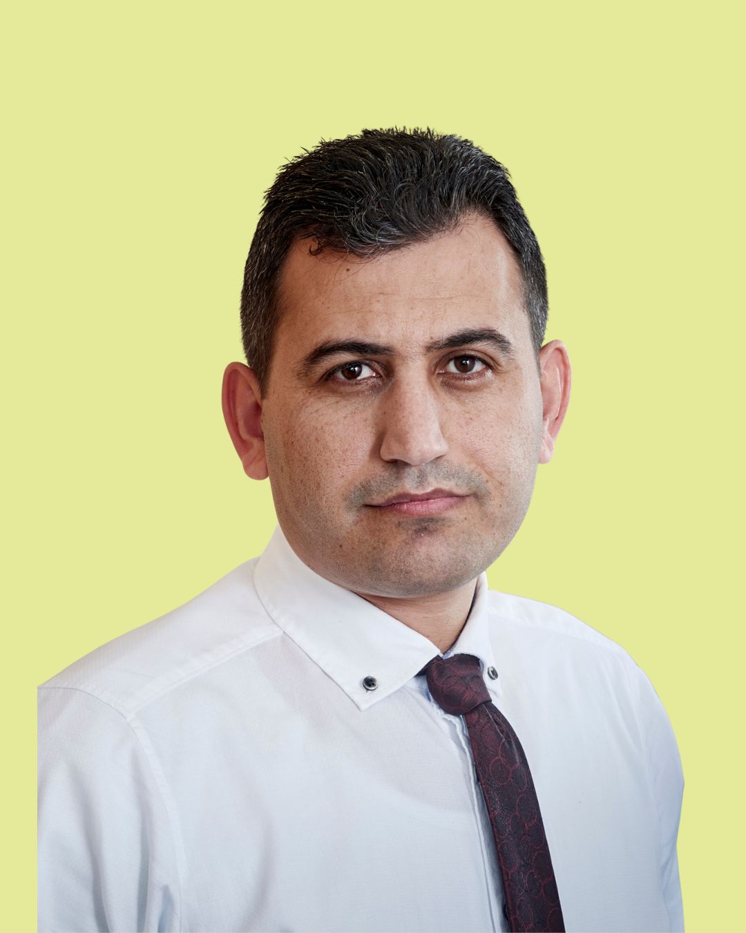 Porträt eines Mannes im Hemd mit Krawatte vor grünem Hintergrund.