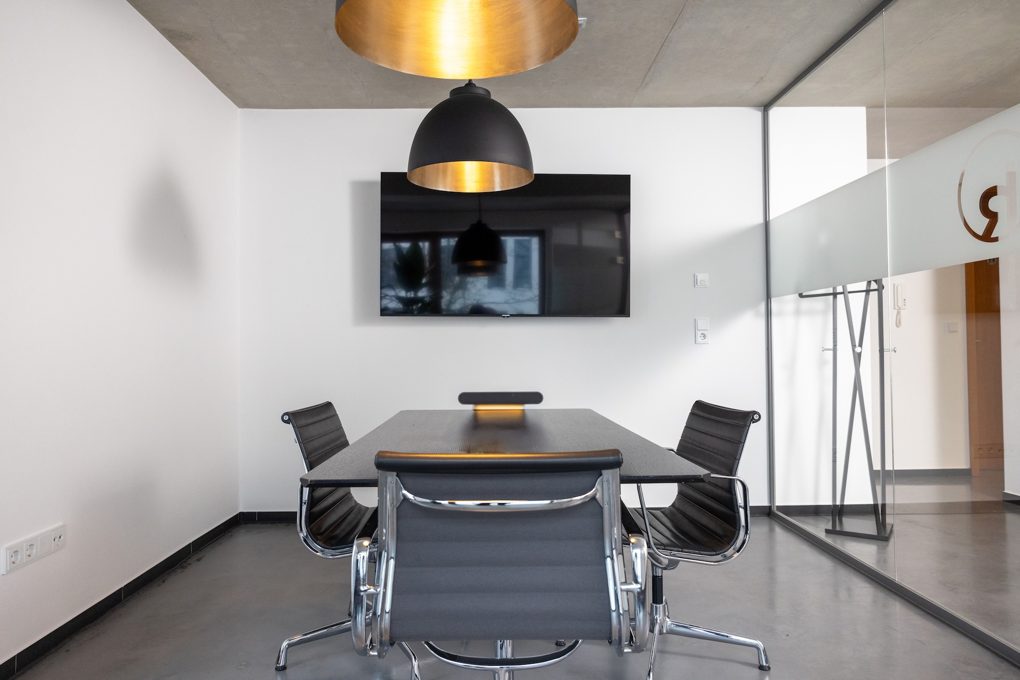 Moderner Konferenzraum mit Tisch und Stühlen, Fernseher an der Wand.