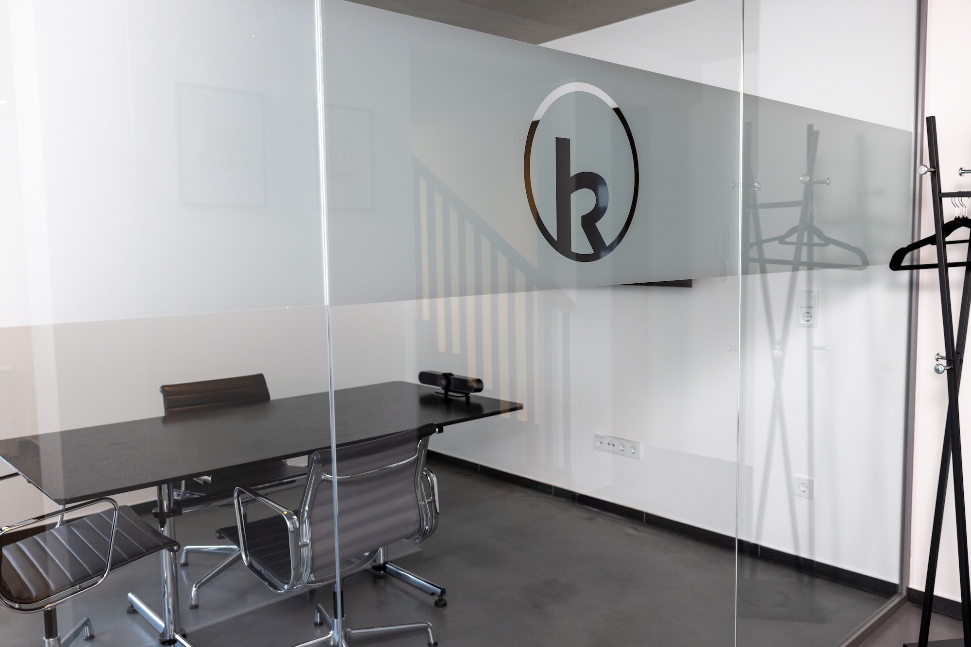 Besprechungsraum mit Glaswand und Logo an der Wand.