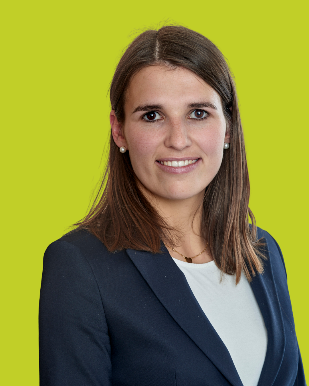 Porträt einer Frau im Blazer vor grünem Hintergrund.