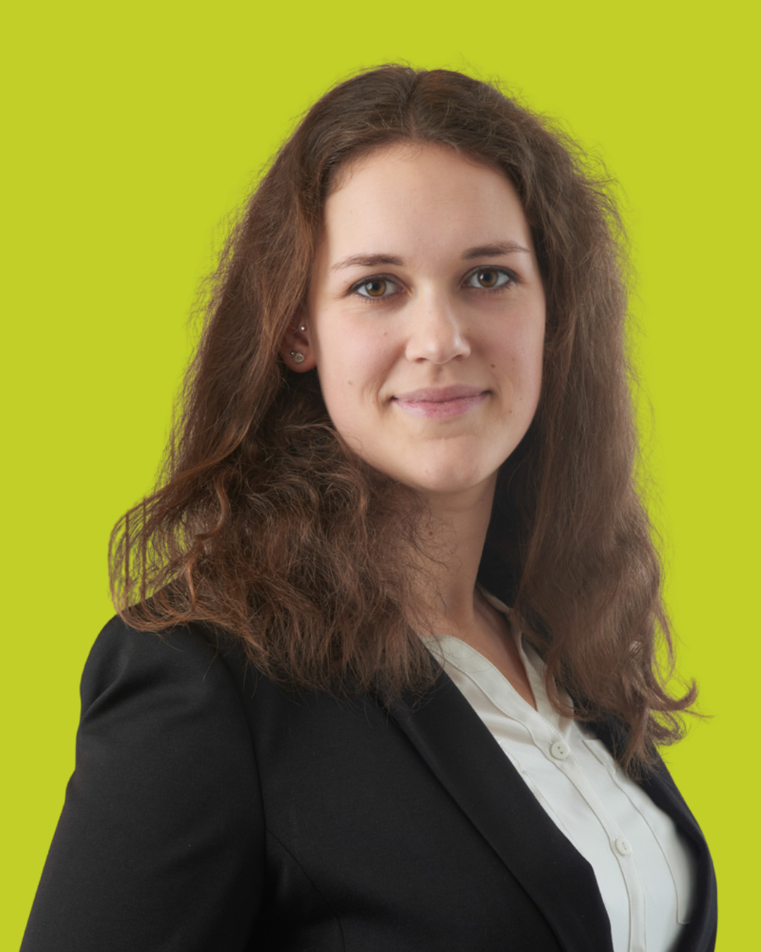 Porträt einer Frau im Blazer vor grünem Hintergrund.