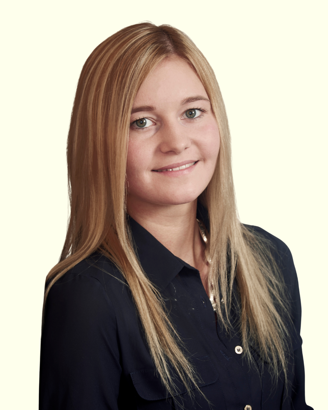 Porträt einer jungen Frau mit langen blonden Haaren vor hellem Hintergrund.