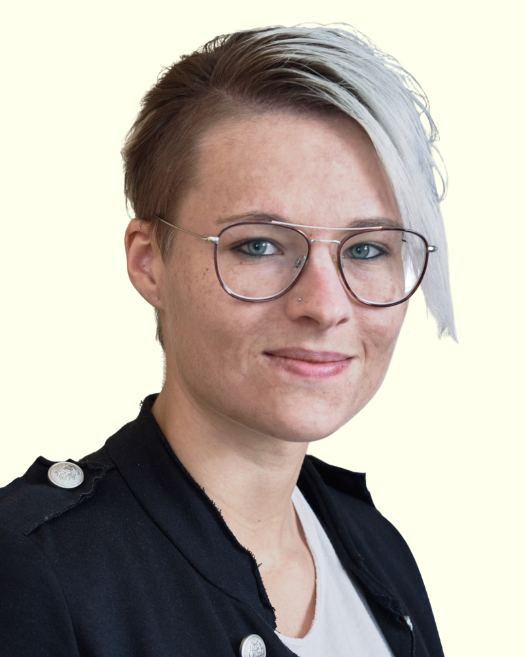 Porträt einer Frau mit Kurzhaarfrisur und Brille vor hellem Hintergrund.