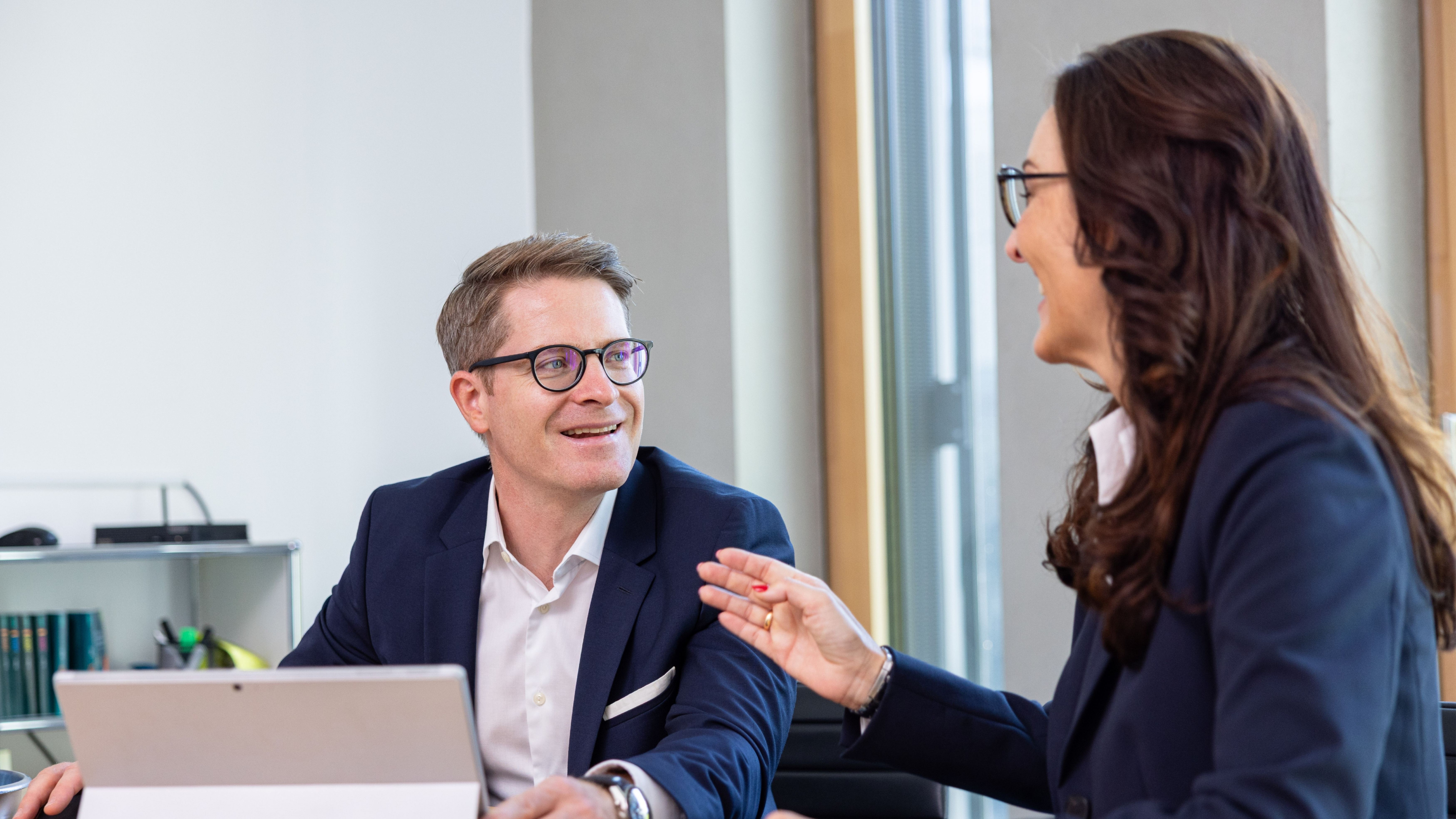 Zwei Personen führen ein Gespräch im Büro, eine Person gestikuliert.