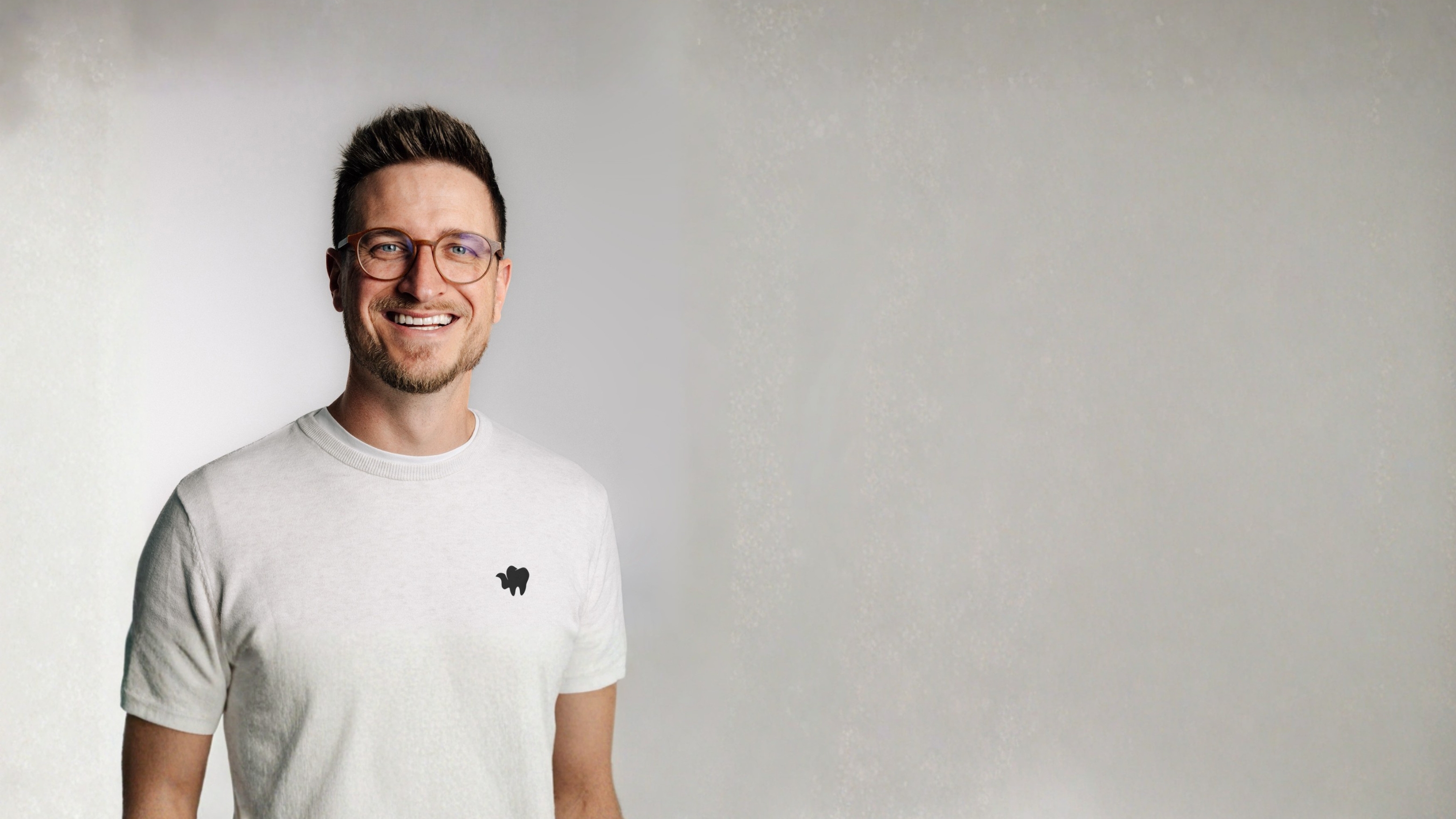 Porträt eines Mannes im weißen T-Shirt vor hellem Hintergrund.