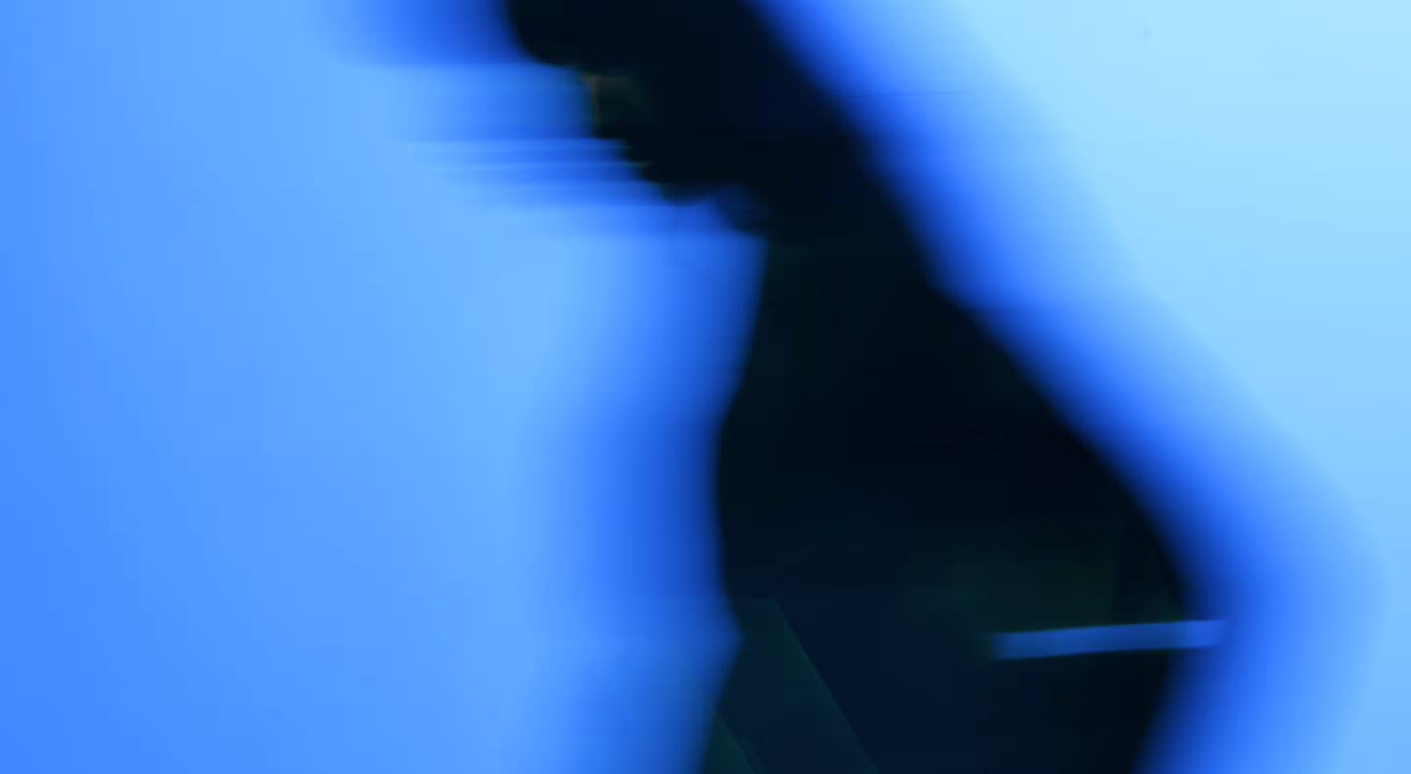 Silhouette floue d'une personne en mouvement sur fond bleu.