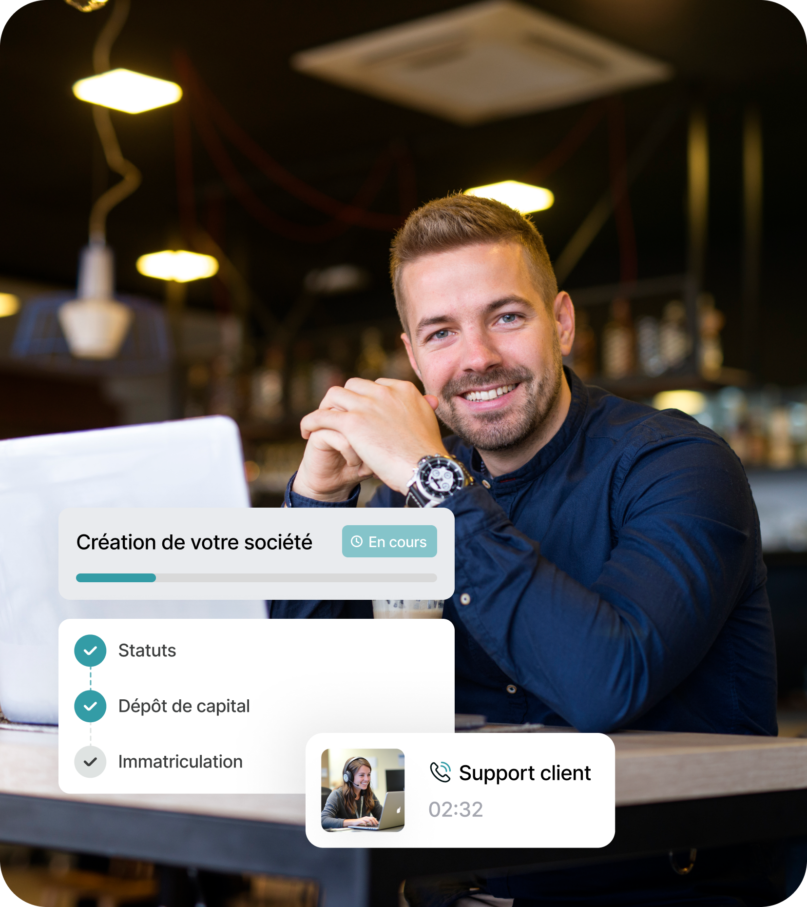 Homme souriant assis à une table avec un ordinateur portable dans un café, avec une interface affichant la progression de la création d'une société et une assistance client en ligne.