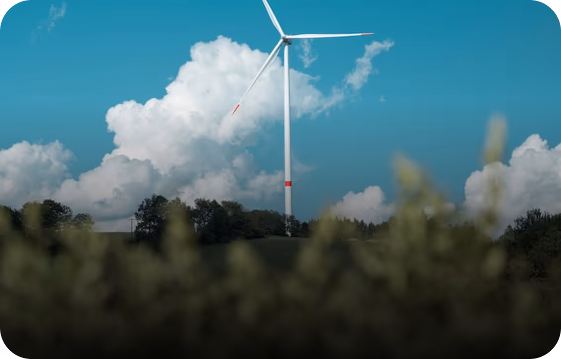 Éolienne blanche sur une colline avec un ciel bleu et des nuages blancs en arrière-plan.