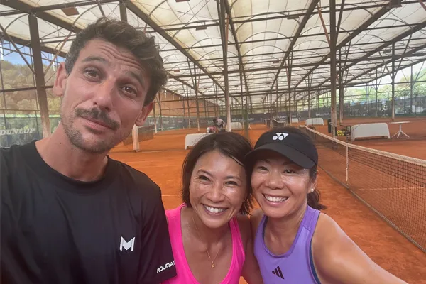 Three athletes posing on a tennis court.