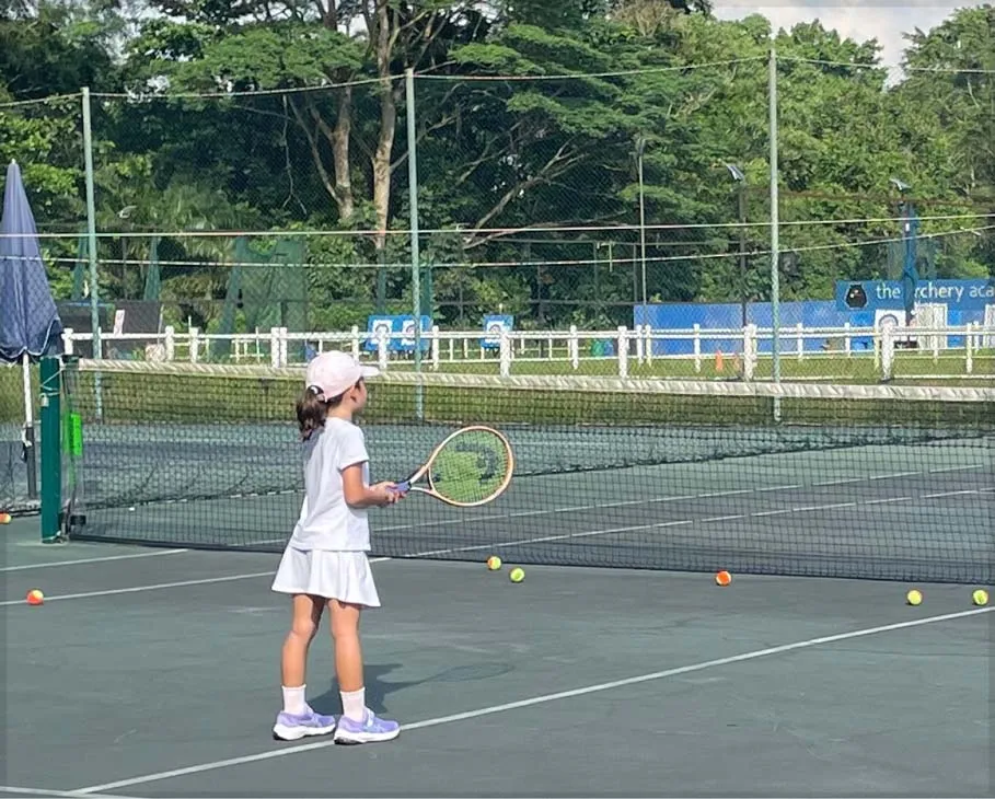 A little girl playing tennis on the court.