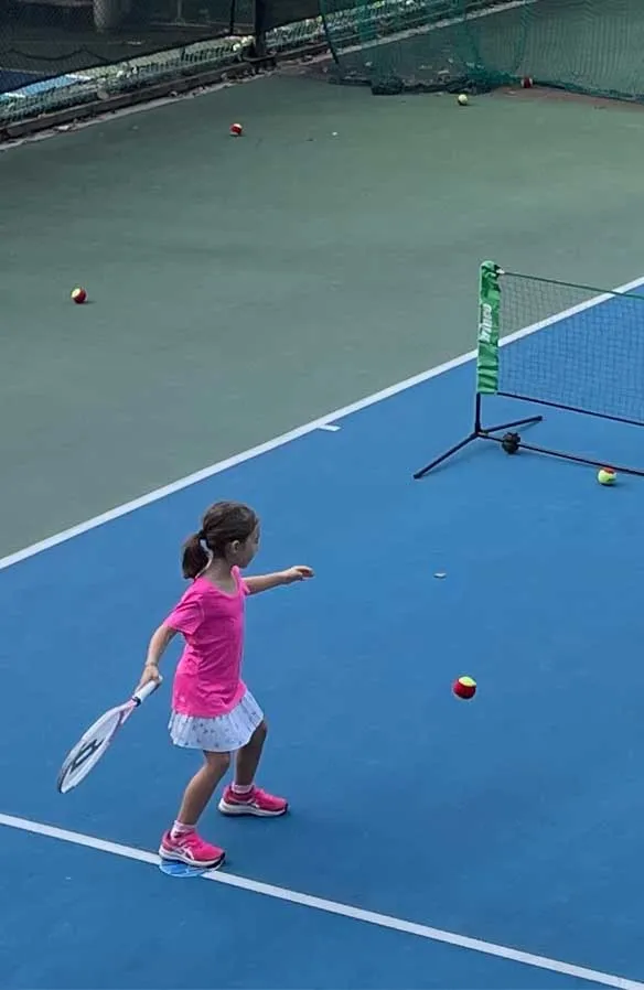 Little girl executing a forehand stroke in a tennis game.