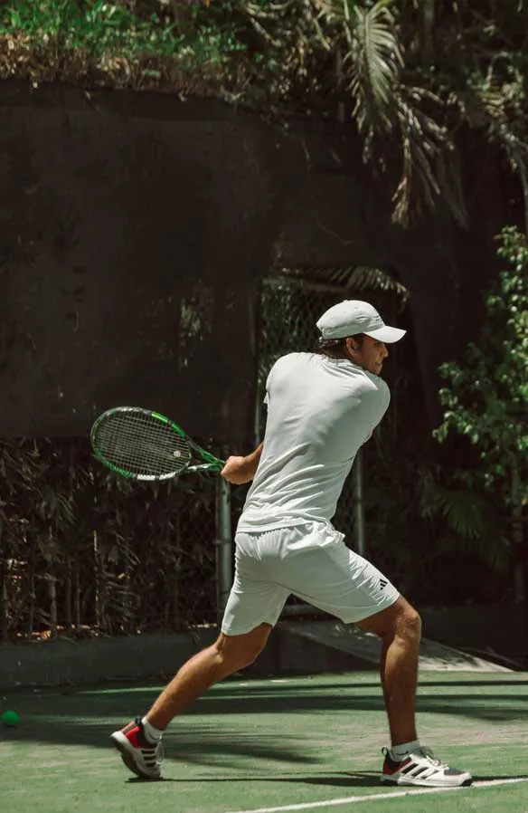 Male tennis player executing a backhand stroke during a game.
