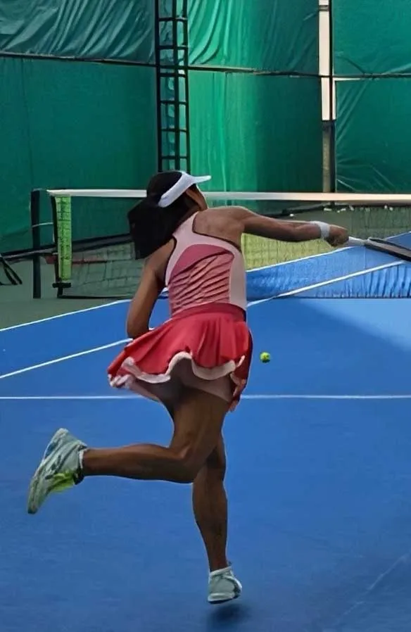 A female athlete playing tennis on the court.