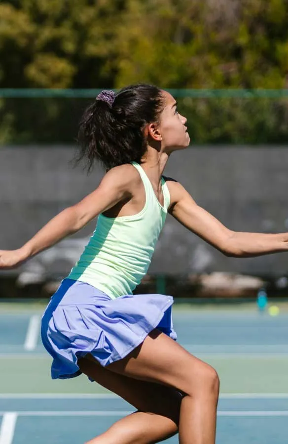 A young girl playing tennis on the court.