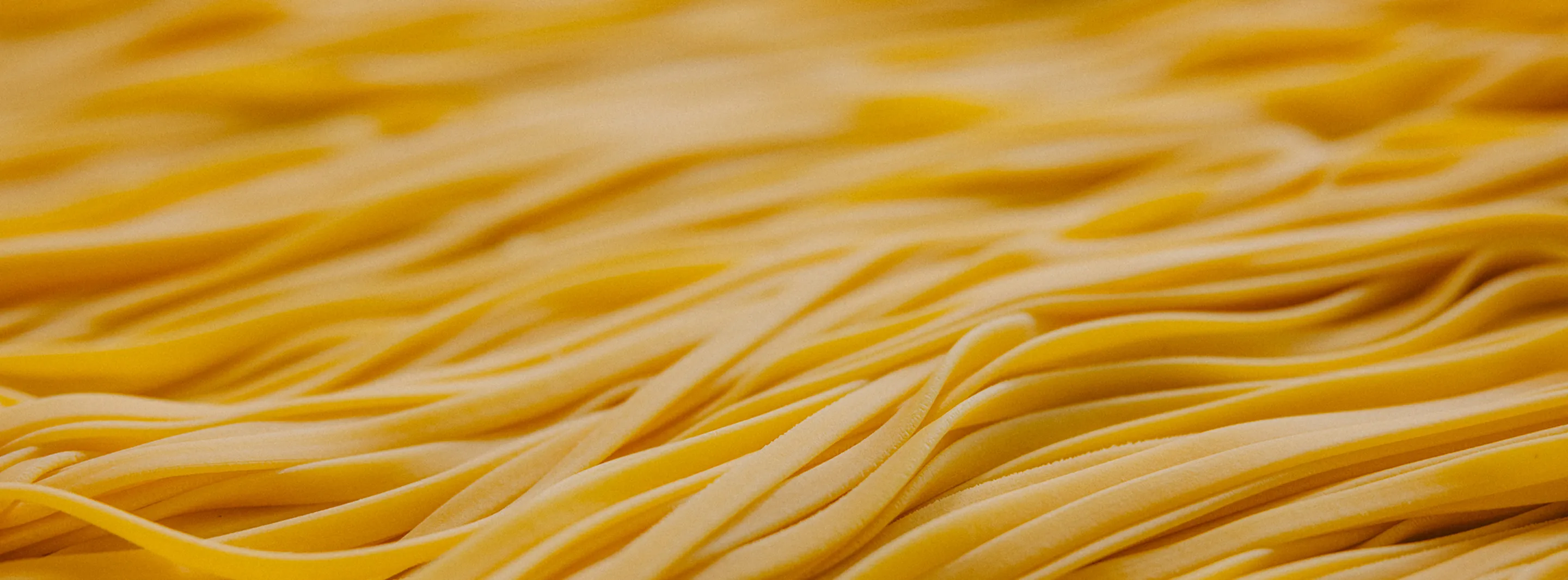 Close-up of raw yellow pasta strands arranged in rows.