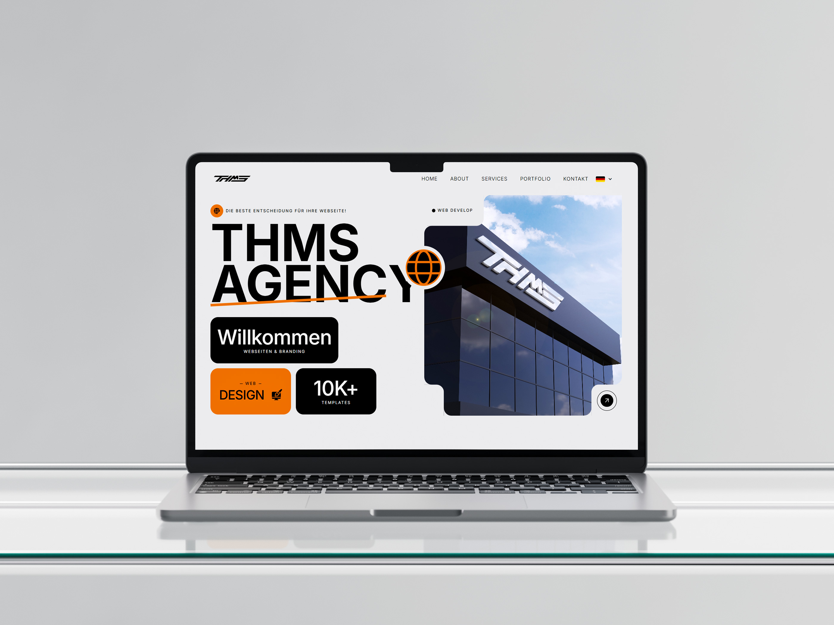 MacBook auf einem modernen Glastisch mit geöffneter THMS-Landingpage im Display sichtbar.