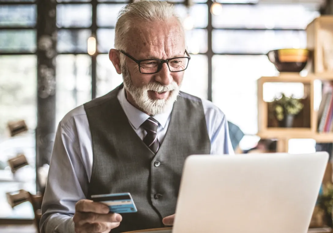 Photo d'un entrepreneur face à un ordinateur avec une carte bancaire dans une main