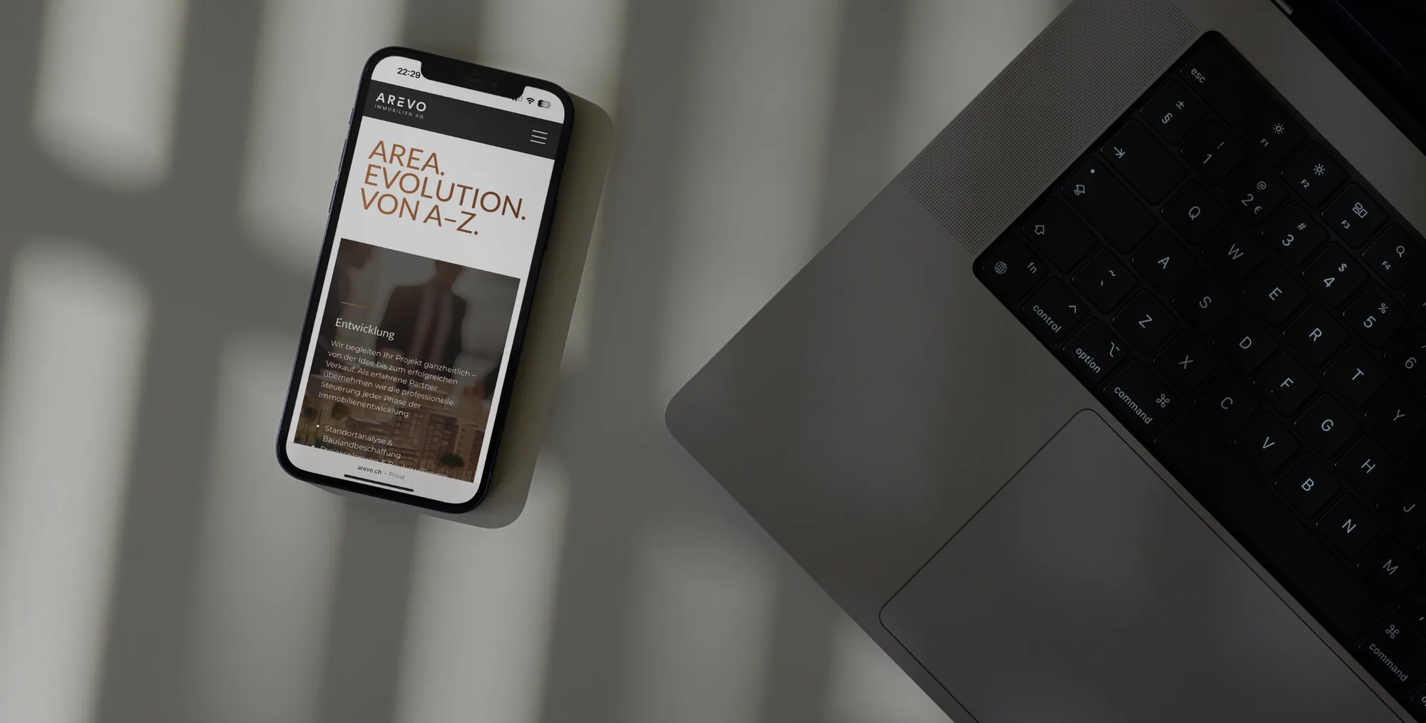 AREVO Immobilien AG – website on a smartphone next to a laptop, showing “Area Evolution”