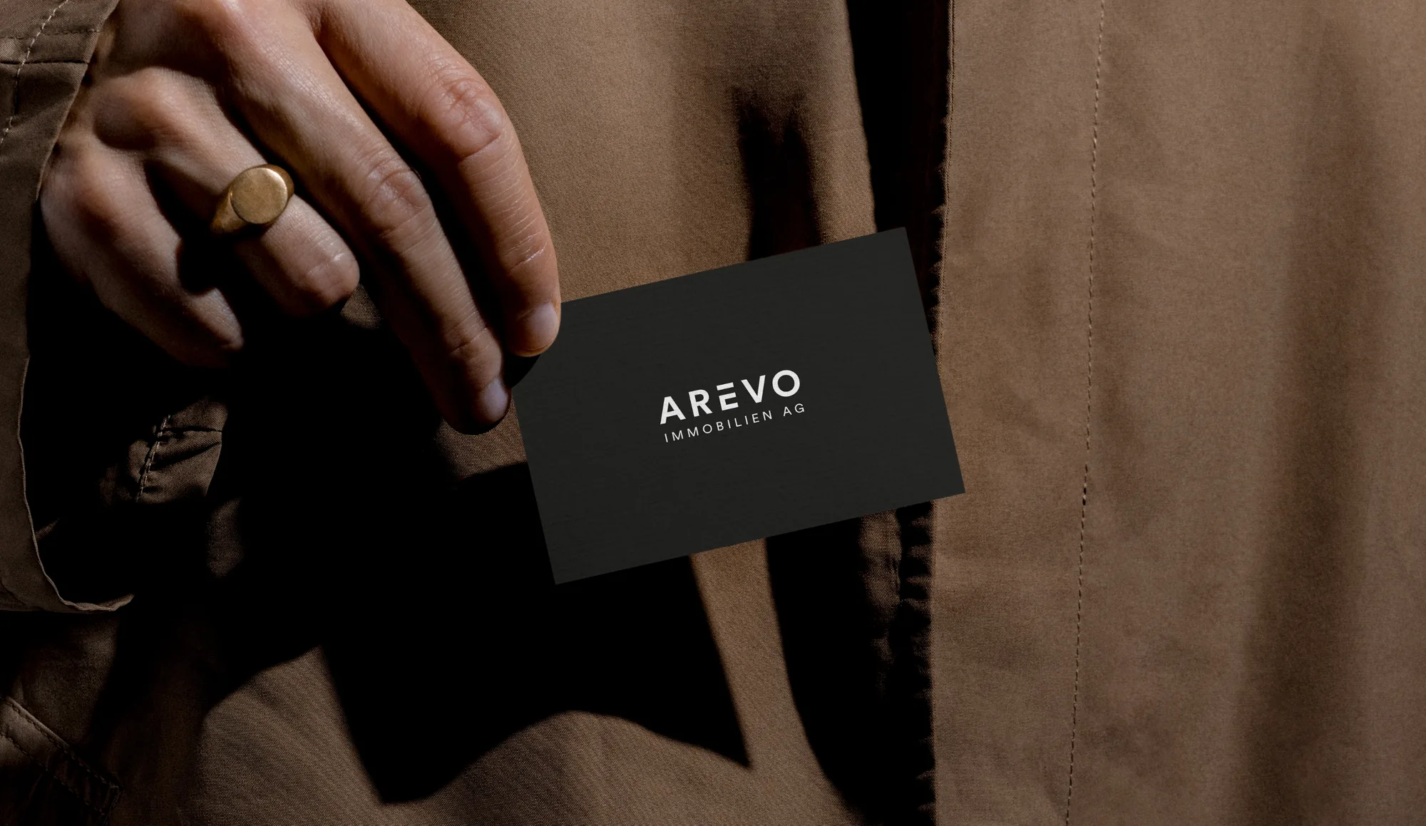 Branding – a hand holding a dark business card against a brown coat