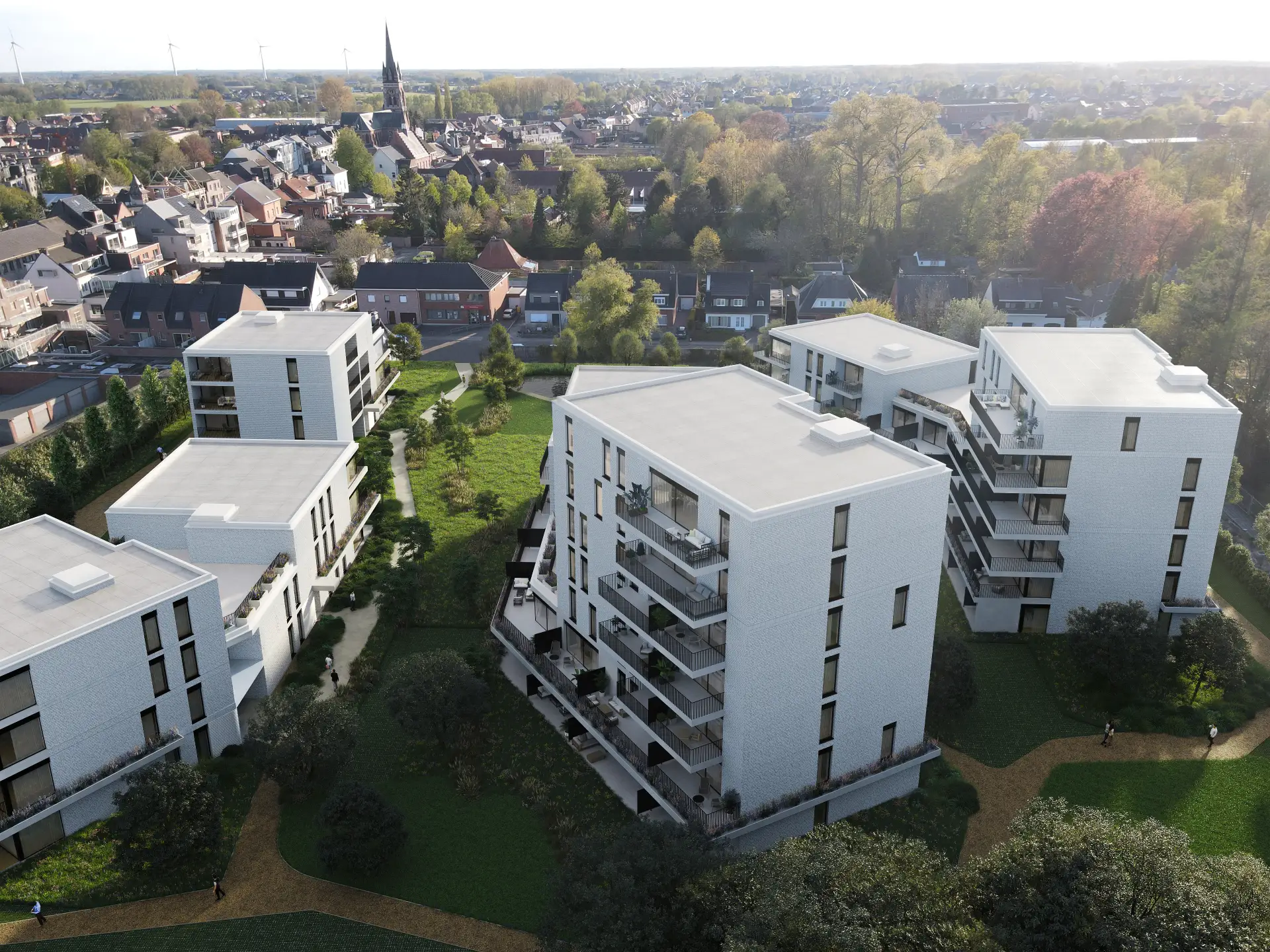 Luchtfoto van modern wooncomplex met meerdere witte appartementsgebouwen omgeven door groen en paden in een stadse omgeving.