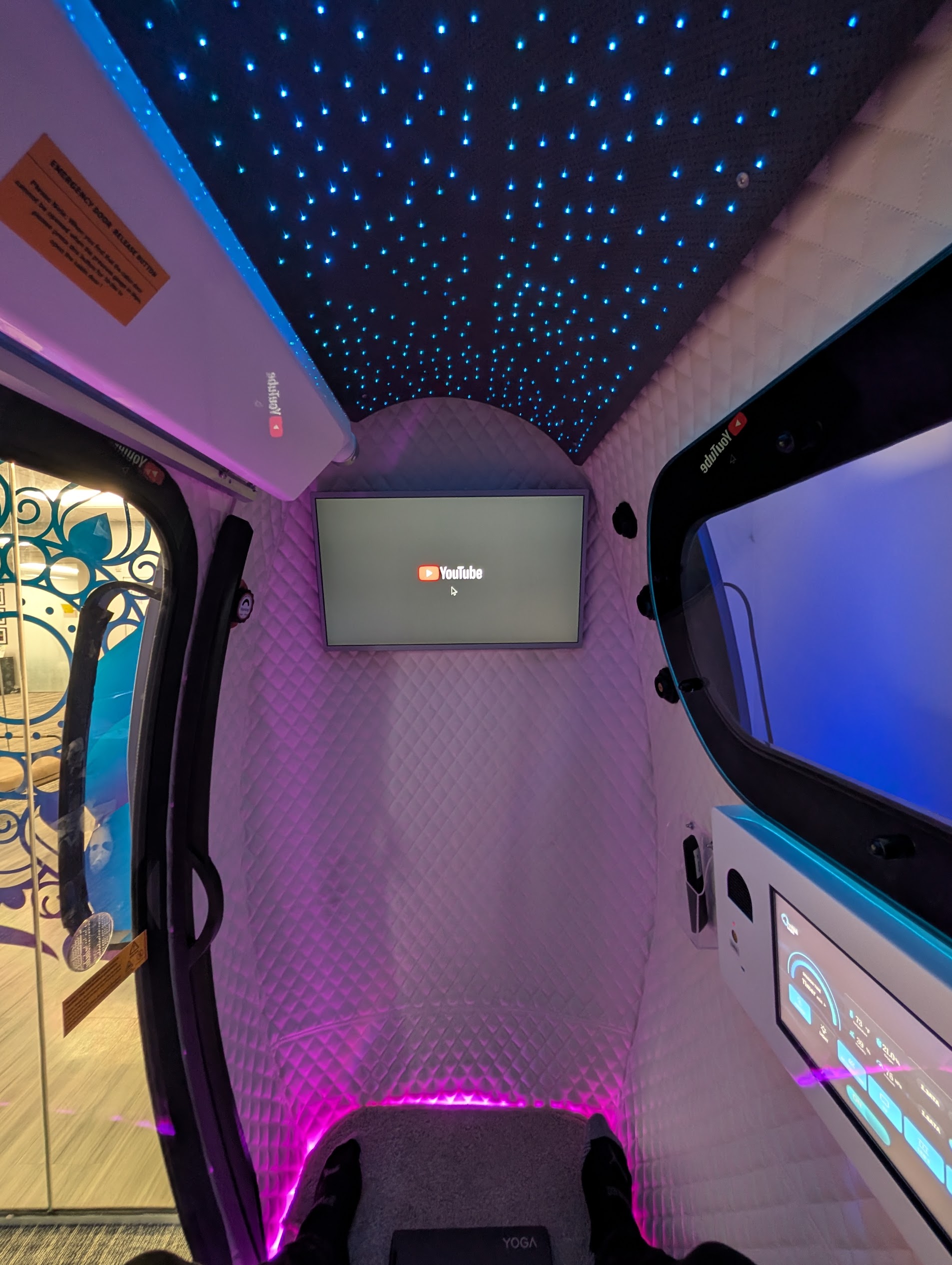 View from the seat inside a Mind Spa hyperbaric chamber, showing padded walls and a lighted ceiling