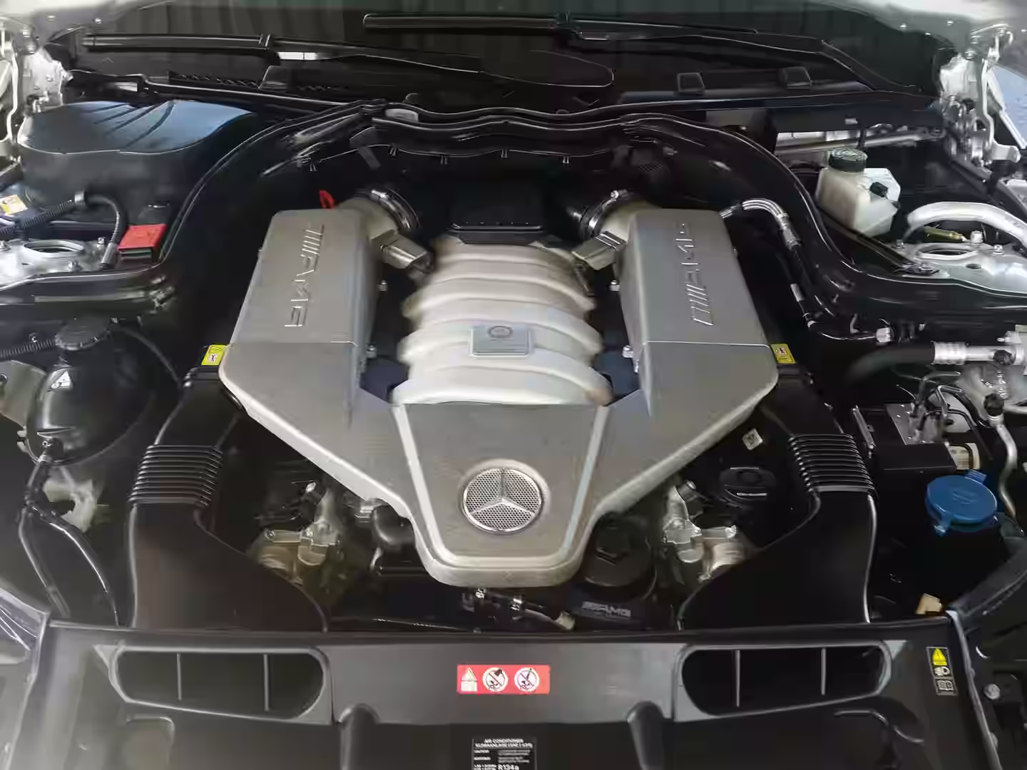 A Motor City Auto Detailing technician carefully steam cleaning an engine bay of a luxury car - mobile car engine steam cleaning near me