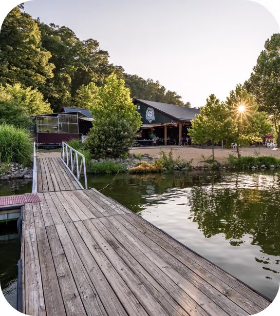 A serene lake dock surrounded by trees, with a charming house nestled in the background, reflecting nature's tranquility.