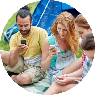 Four individuals seated on the grass, each focused on their smartphones