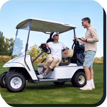 A man and woman stand beside a golf cart
