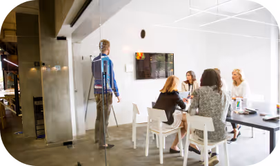 A diverse group of individuals engaged in discussion around a conference table in a professional setting.