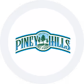 Official Piney Hills RV Park logo featuring green pine trees and blue arched typography.