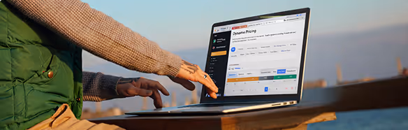 A professional using a laptop outdoors to manage dynamic pricing and occupancy rules for a campground or RV park.