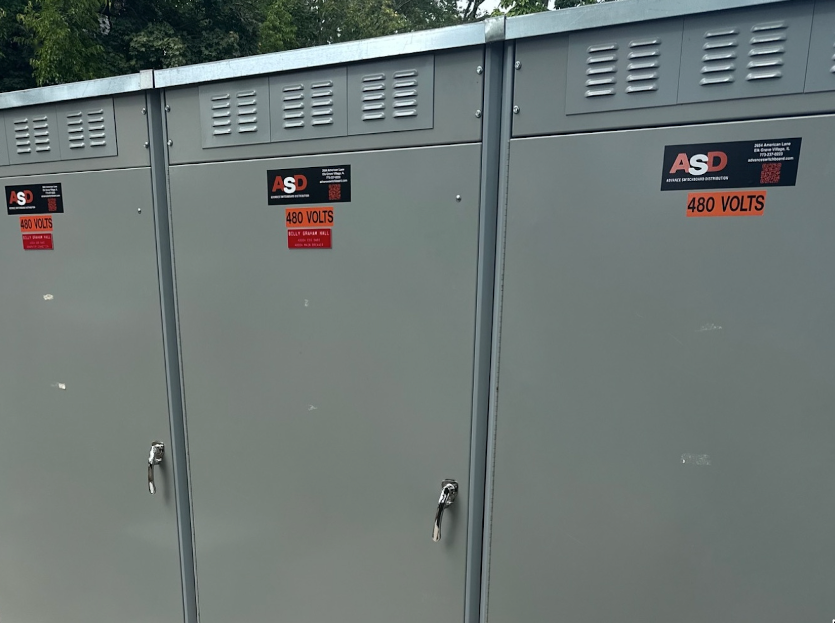 Outdoor electrical switchgear lineup with three 480-volt gray metal enclosures.