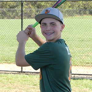 A waist up shot of Elkridge Hurricanes player Aiden Marll in his batting stance looking at the camera.