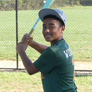 A waist up shot of Elkridge Hurricanes player Kaden Wooden in his batting stance looking at the camera.