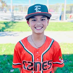 Headshot of Elkridge Hurricanes player Trenton Huynh wearing his orange Canes baseball jersey and green Elkridge E logo hat.