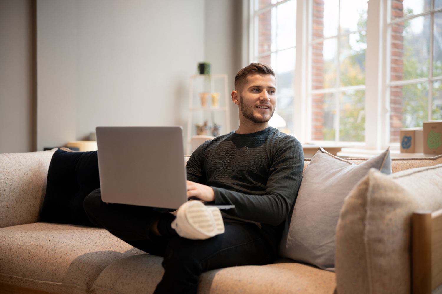 Man sitting on a sofa with a laptop on his lap, working remotely